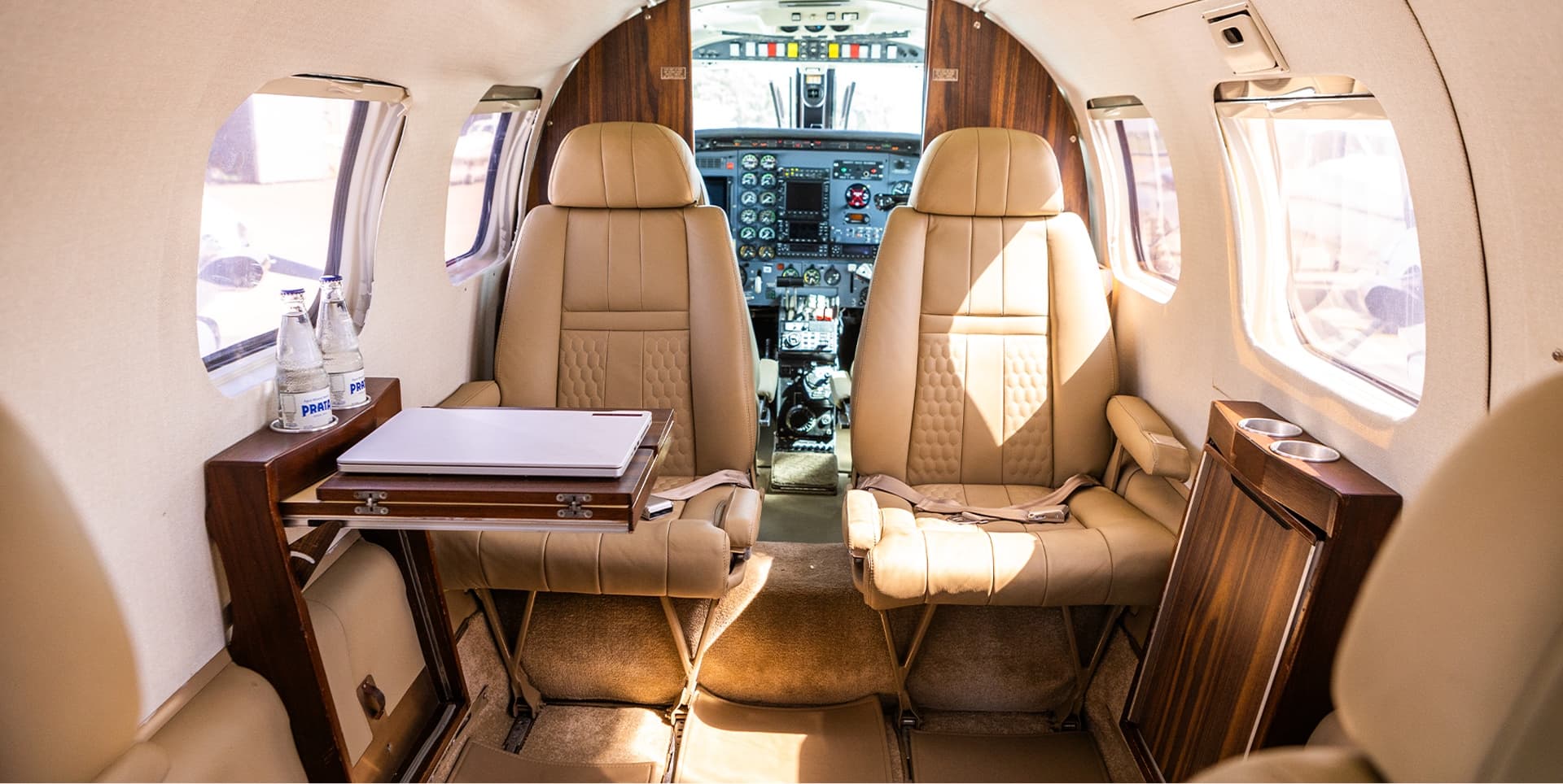 Cabine executiva de uma aeronave da Abelha, com poltronas de couro e mesa de trabalho.